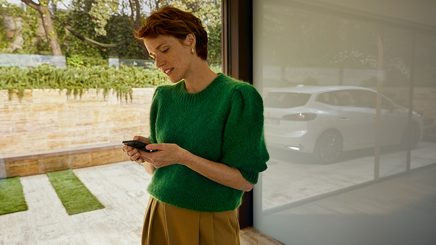 Woman holding smartphone BMW Service Inclusive