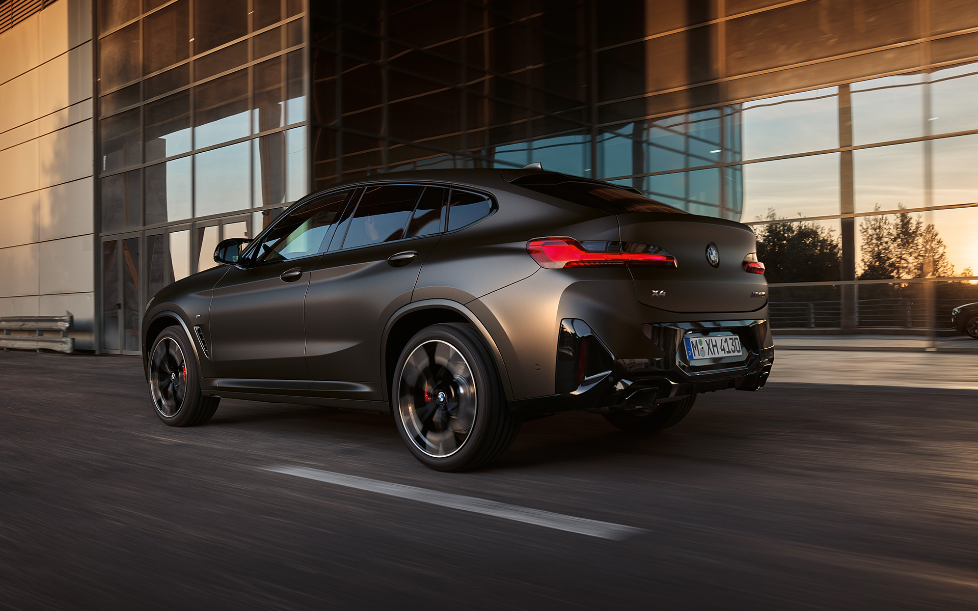 BMW X4 M40i G02 LCI 2021 Facelift three-quarter rear view in front of glass facade
