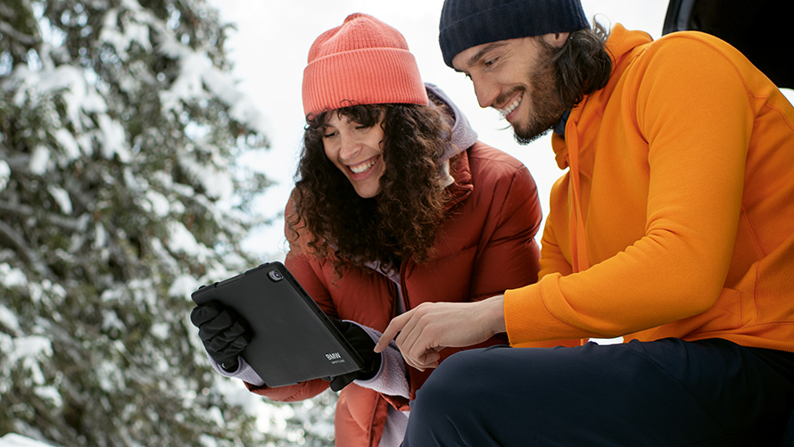 Woman and man in snow looking at tablet 