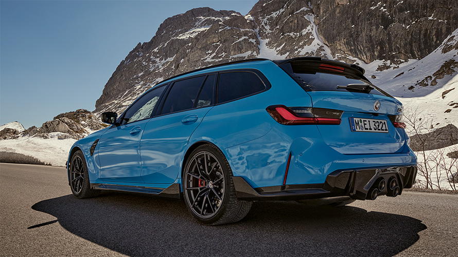 BMW M3 Touring G81 BMW M Performance Parts three-quarter side view driving in front of mountain landscape