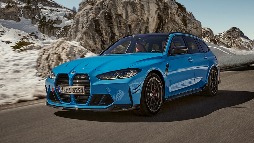 BMW M3 Touring G81 BMW M Performance Parts three-quarter front view driving in front of mountain landscape