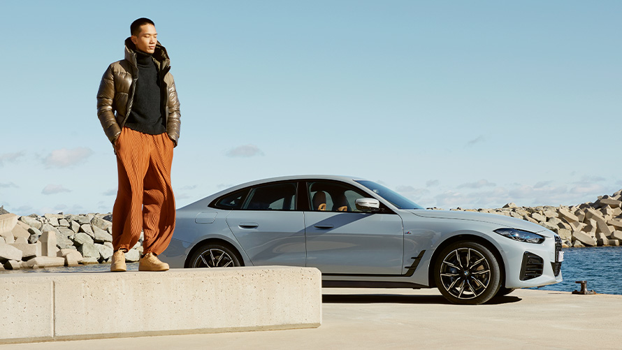 BMW Service Inclusive BMW G26 Man standing on stone edge with BMW vehicle in background