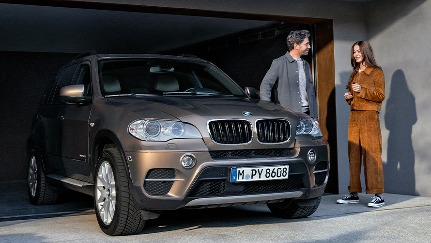 BMW Value Service BMW X2 G05 Man and woman standing next to BMW vehicle on garage driveway