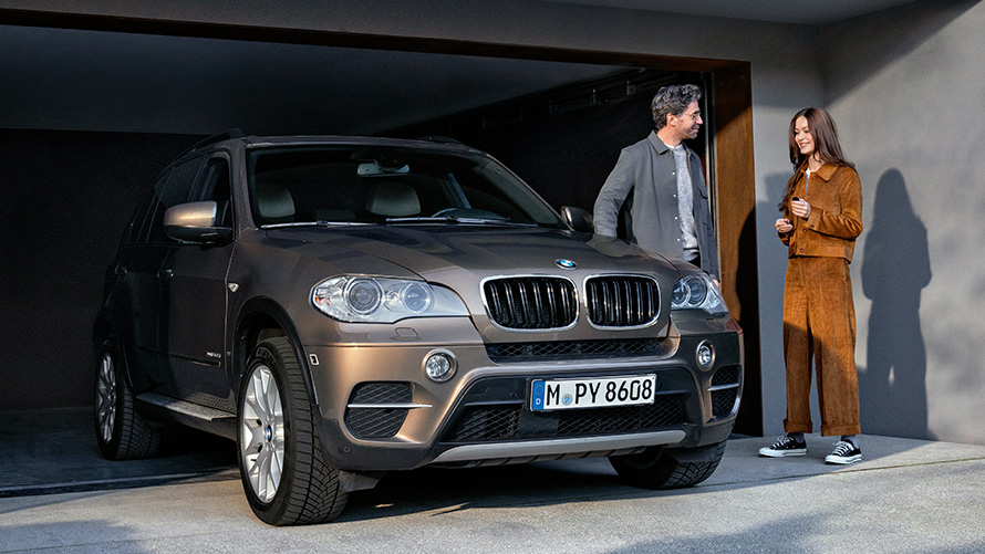 BMW Value Service man and woman in front of garage with BMW X5